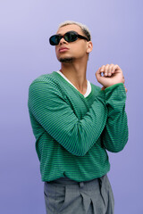 Fashionable young man with dyed hair showcases style against a vibrant purple backdrop