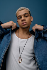 Stylish young Black man flaunting a denim jacket on a bold blue backdrop