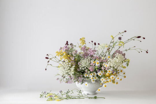 summer wild flowers in white teapot on white background