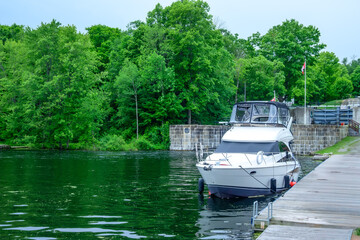 Fototapeta premium A motor cruising yacht sits moored at the bottom of a lock system in summer shot jones falls on the rideau canal system