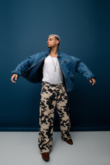 A young african american man with dyed hair confidently poses in a trendy denim jacket