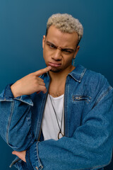 Stylish young man with dyed hair poses confidently against a blue backdrop