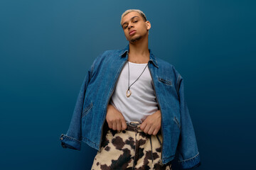 Confident young man with dyed hair showcasing denim style on a bold blue backdrop