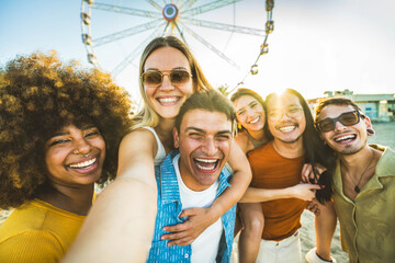 Multiracial group of friends taking selfie with smart mobile phone outside - Happy young people having fun in front of ferris wheel at summer vacation - Technology and summertime holidays concept