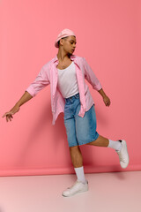 Stylish young african american man showcases fashion on playful pink backdrop