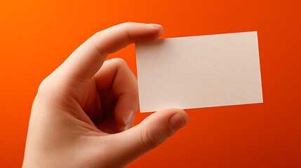 Child’s hand holding business card on pure orange background