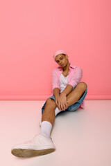 Young man exudes style in beret and checkered shirt against pink backdrop