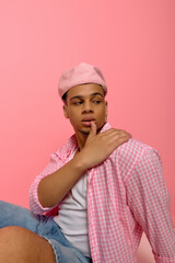 Stylish young man showcases vibrant fashion on a playful pink backdrop