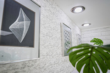 Close-up of a white and silver vintage wallpapered wall featuring framed chrome op art, modern...