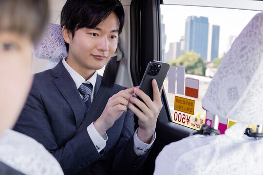 タクシーの後部座席でスマホを使うビジネスマン
