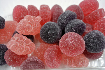 Cherry, red, purple, pink, delicious candies in the form of fruits, currants, grapes, raspberries, blueberries, strawberries. A variety of jelly sweets, all colors of candy are on white background.