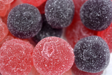 Cherry, red, purple, pink, delicious candies in the form of fruits, currants, grapes, raspberries, blueberries, strawberries. A variety of jelly sweets, all colors of candy are on white background.