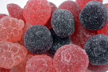 Cherry, red, purple, pink, delicious candies in the form of fruits, currants, grapes, raspberries, blueberries, strawberries. A variety of jelly sweets, all colors of candy are on white background.
