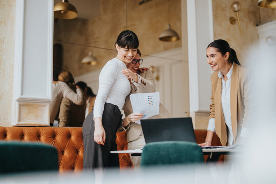 A group of female business professionals engaged in teamwork in a stylish office environment, demonstrating collaboration and professionalism. - Powered by Adobe