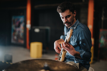 A performer is playing the guitar during a rehearsal, preparing for an upcoming concert in a professional studio. The setting reflects creativity and dedication to musical artistry in a lively