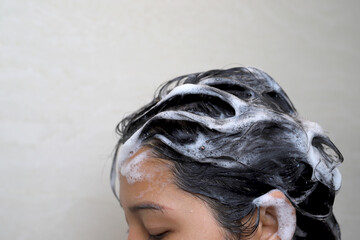 A woman is taking a shower and washing her hair in the bathroom.