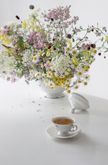 cup of tea with wild flowers on white table