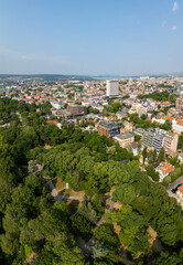 Aerial panoramic view of Varna, Bulgaria, showcasing the urban landscape with red rooftops, green parks, and the Black Sea in the distance under a clear blue sky
