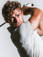 Muscular male golfer demonstrating perfect swing technique on the course