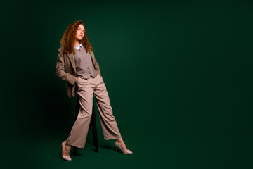 Confident businesswoman posing in a formal outfit on an emerald background showing professional and...