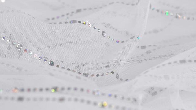 White tulle fabric with silver glitters. Textile material tissue cloth background. Texture fabric close up. Fabric for wedding dress