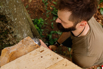brutal young brunette man, dad with beard is nailing building a tree house to his little son with...