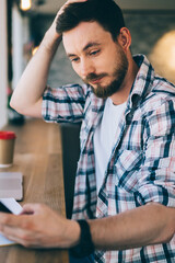 Puzzled man checking mobile phone