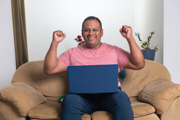 A man is sitting on a couch with a laptop in front of him
