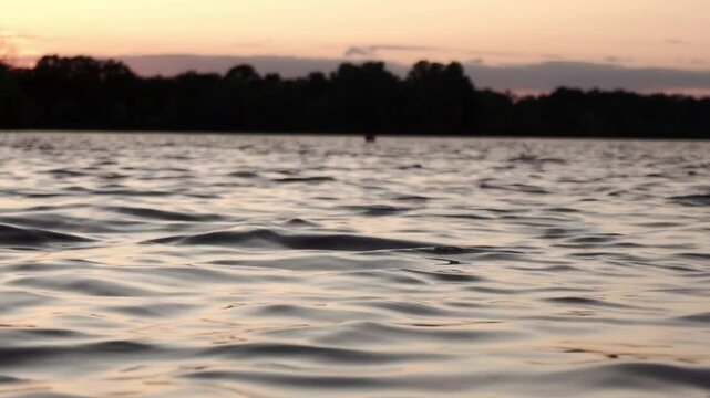 Soothing footage of gentle waves rippling across a calm river surface. Shot without visible shoreline, this seamless water texture is ideal for use as a natural background