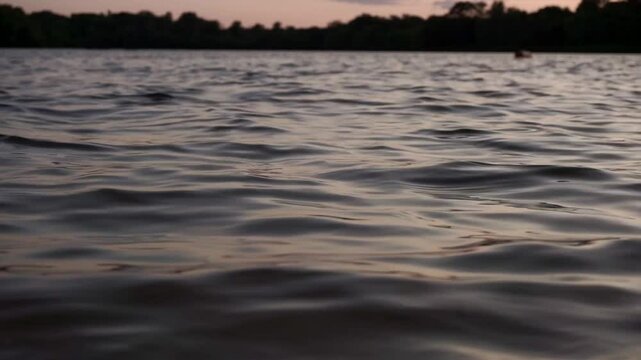Soothing footage of gentle waves rippling across a calm river surface. Shot without visible shoreline, this seamless water texture is ideal for use as a natural background