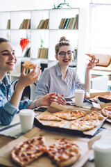 Women eating pizza and speaking to friend at table