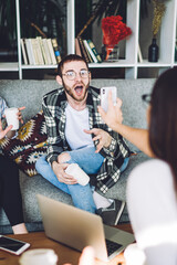 Shocked casual man responding on news demonstrating on friends smartphone