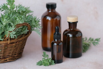 Brown glass bottles filled with essential oils are placed on a soft backdrop, accompanied by a...