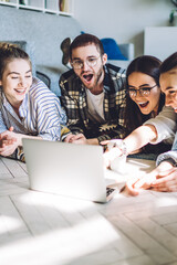 Cheerful young man and women using laptop on floor at home