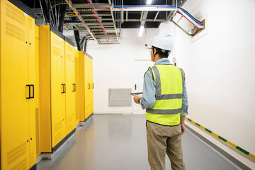 asian electrical engineer is performing inspection in substation control room