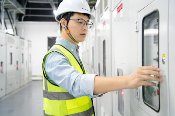 asian electrical engineer is performing inspection in substation control room