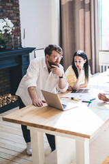 Creative multiracial people looking at laptop during work in light room