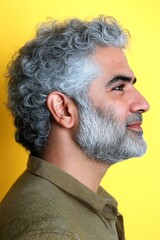Fototapeta premium Visual idea of style for aging men. Chic men's hard part haircut - midlife middle eastern man with curly hair. Yellow solid background. A studio glamour portrait of a confident man.