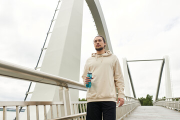 Sporty young man jogging outdoors on a scenic bridge in comfortable attire