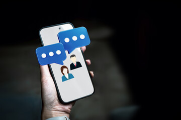 Smartphone mobile chatting with screen showing two profile icons and blue speech bubble. Concept of online communication, and customer service.