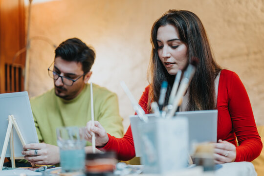 A man and a woman joyfully engaging in a painting activity, sharing a creative moment together indoors.