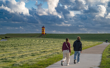 Touristen auf dem Weg zum Pilsumer Leuchtturm in Ostfriesland, Deutschland