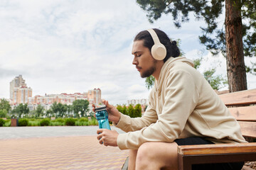 Young sporty man enjoying a workout break while listening to music outdoors