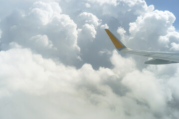 Wing of passenger airplane flying above dense cumulus clouds. Start of vacation: aerial view taken...