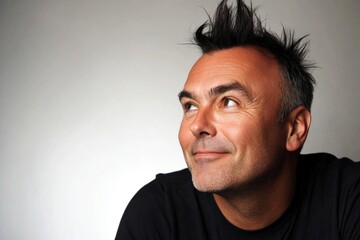 Obraz premium Pure white solid background. A gentle smile lighting up a maleâ€™s face. Creative of style for aging men. Fashionable men's short punk haircut - midlife white man with black hair.