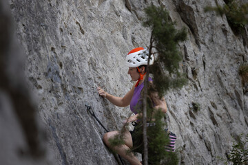 A woman is climbing a rock wall wearing a helmet
