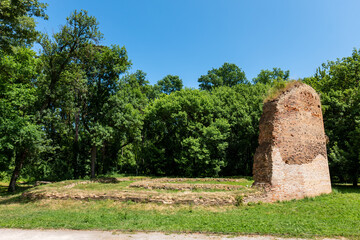 Ruins of Parič water castle from 13th century in Trebišov city park, historical site with brick walls surrounded by trees and grass, sunny day peaceful setting. © Marek