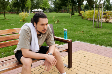 Young sporty man taking a break after outdoor workout at a serene park