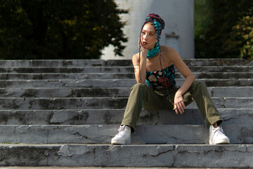 Fashionable female with extended braids and a vibrant head wrap posing outdoors