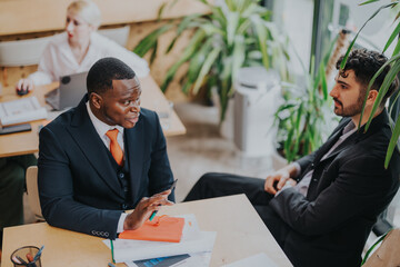 Business people collaborating in a well-lit modern co working space surrounded by greenery,...
